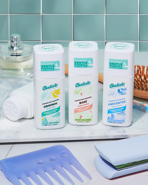 Three Batiste Dry Shampoo Powders are displayed in a bathroom alongside other hair styling tools.