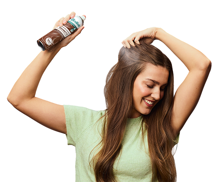 Woman spraying dry shampoo bottle.
