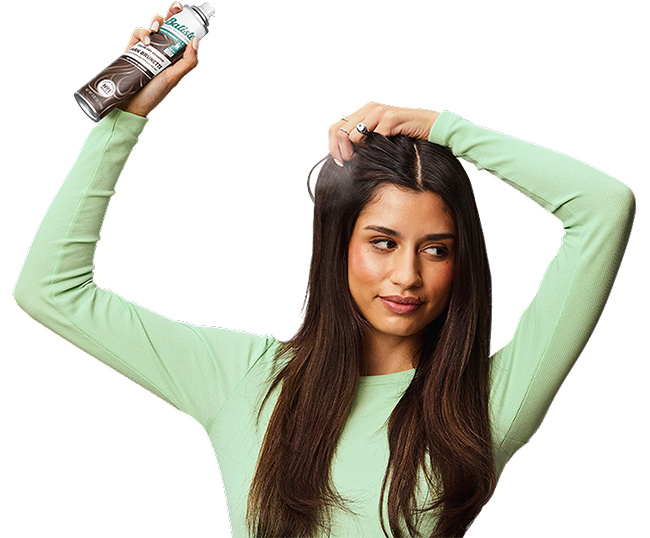 Woman spraying dry shampoo bottle.