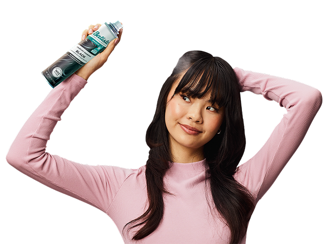 Woman spraying dry shampoo bottle.