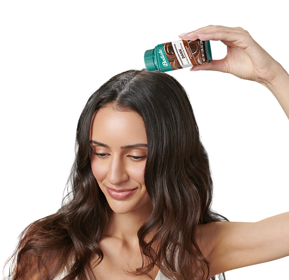 Woman spraying dry shampoo bottle.