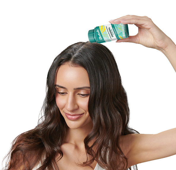 Woman spraying dry shampoo bottle.
