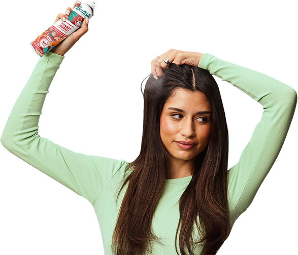Woman spraying dry shampoo bottle.