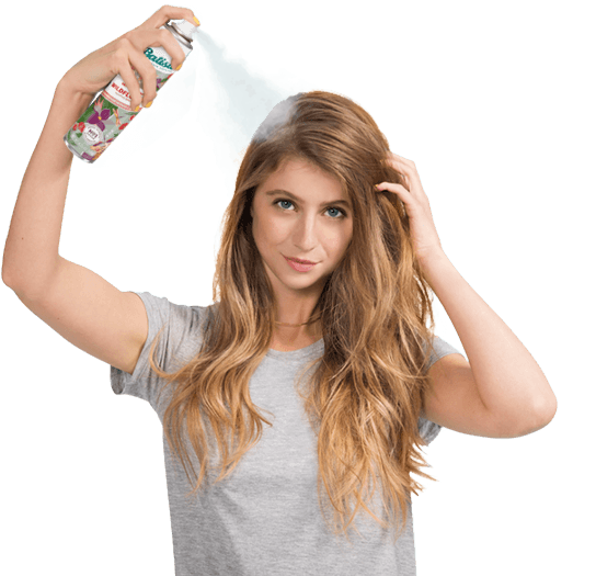 Woman spraying dry shampoo bottle.