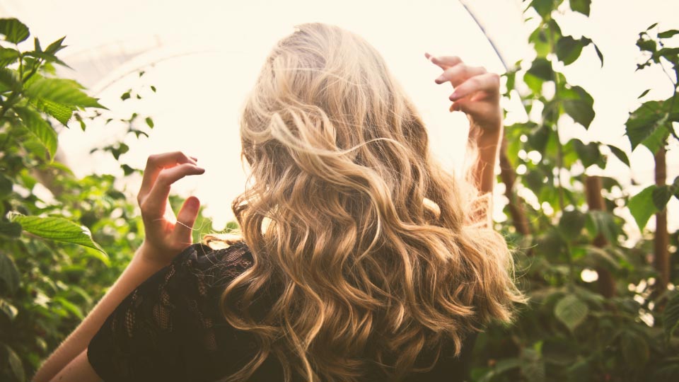 Blonde woman near bushes.