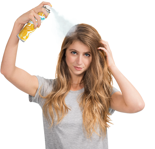 Woman spraying dry shampoo bottle.